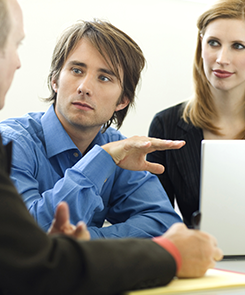 Three Employees Talk Near a Desk